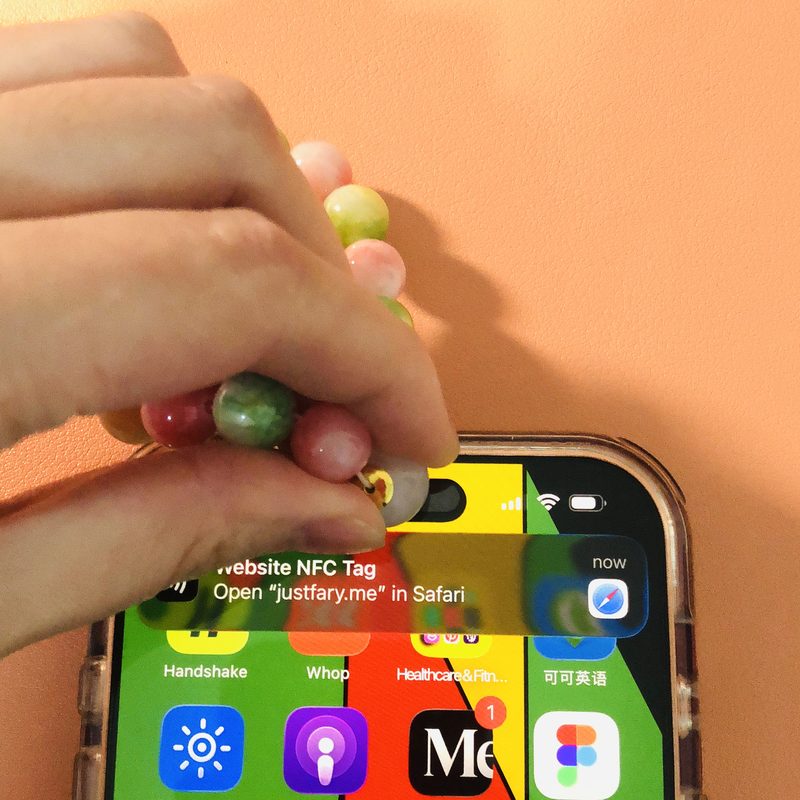 Metal ends of the main bead held to the top of an iPhone, with the NFC notification showing